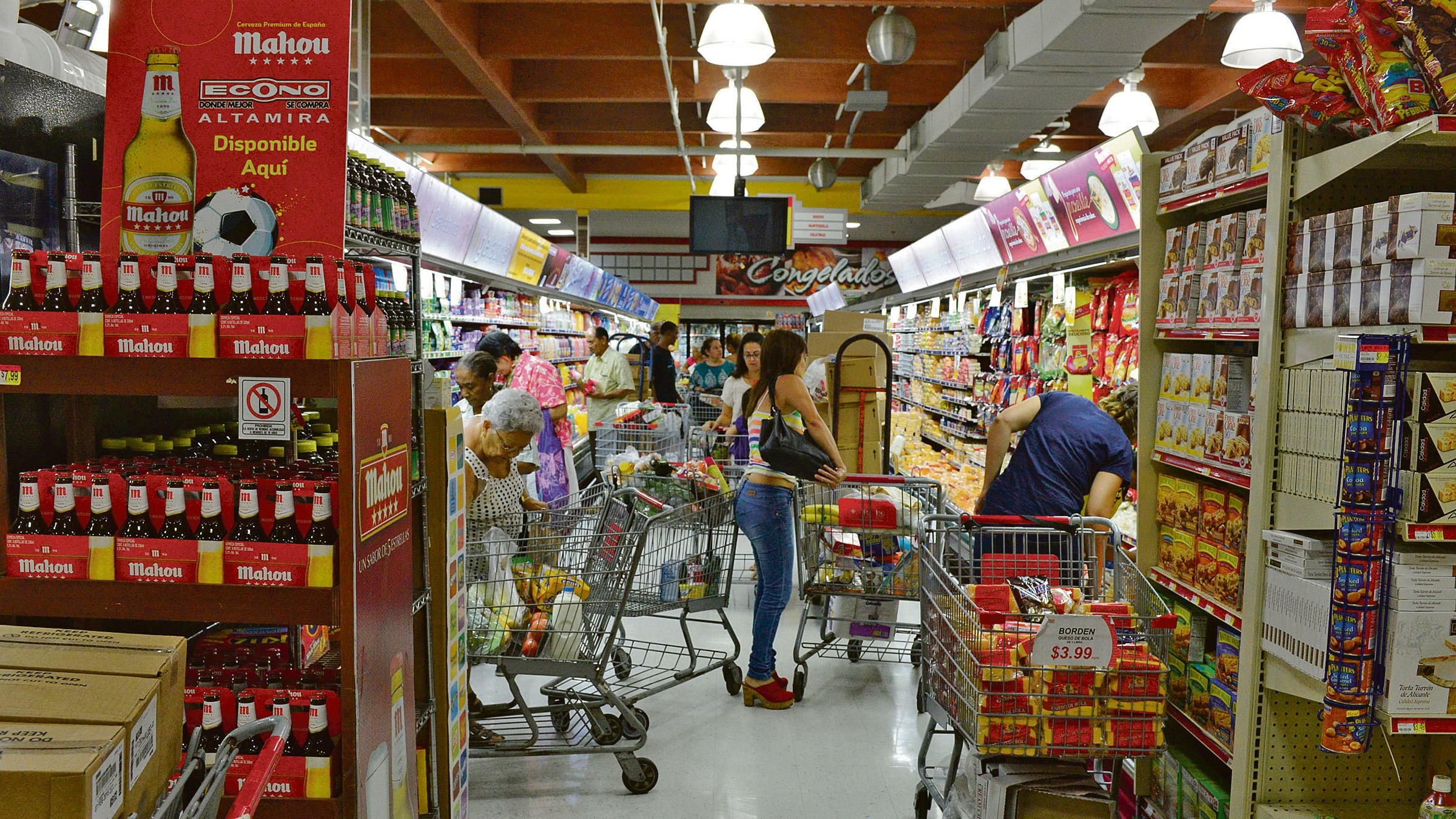 En la góndola de un supermercado, más de cinco personas o familias hacen compra con sus carritos atravesados en el pasillo.